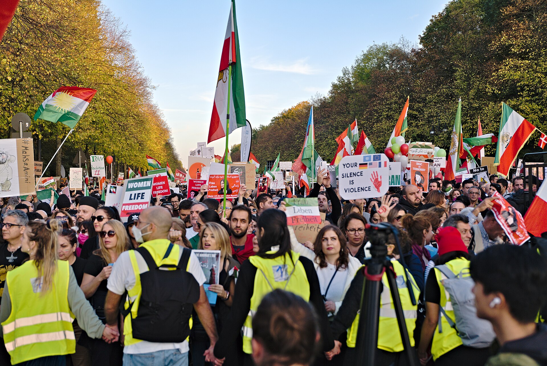 Iranians rally in Berlin in 2026 carrying flags and portraits of people killed in Iran.